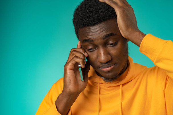 Black man with a sad face talking on the phone in studio - Zdjęcie, obraz