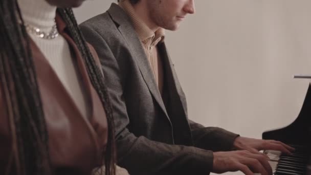 Tilt Slowmo von talentierten jungen interrassischen Musikern, die zusammen ein Klavier im Klassenzimmer der Musikschule spielen - Filmmaterial, Video