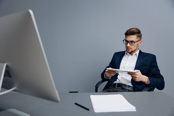 manager seduto a una scrivania davanti a un computer sfondo grigio - Foto, immagini