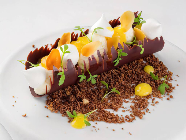 Dessert made from crisp chocolate tuile stuffed with orange and almond cream, cocoa croquant and served on white background - 写真・画像