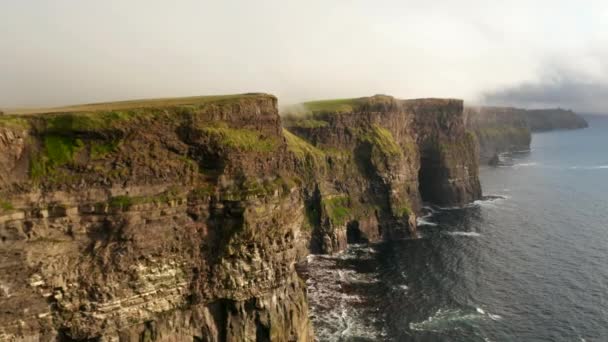 Vlieg boven zee aan de kust. Hoge rotsachtige kliffen boven geklonken water. Adembenemend panoramisch natuurlijk landschap. Kliffen van Moher, Ierland - Video