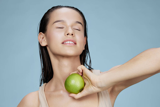 young woman green apple near face health blue background - Photo, Image