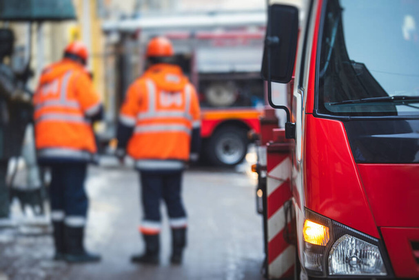 Group of fire men in uniform during fire fighting operation in the city streets, firefighters with the fire engine truck fighting vehicle in the background, emergency  - 写真・画像