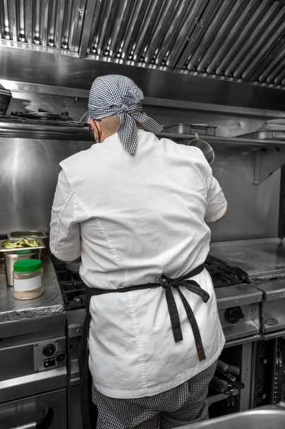 Back view of woman chef cooking food in the kitchen of a restaurant. - Φωτογραφία, εικόνα