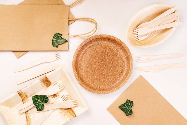 Recycling,eco-friendly concept.Disposable eco cutlery,plates,spoons,knives,forks on a light background.Craft paper bag for food delivery.Copy space.Eco craft paper tableware,cups,fast food containers. - Photo, image