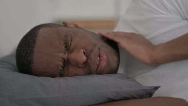 Primo piano dell'uomo africano che ha dolore al collo mentre dorme a letto - Filmati, video