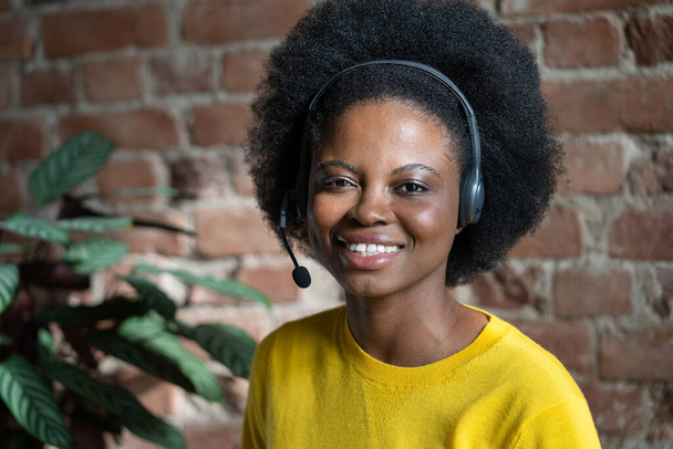 Happy Black woman with headset posing over brick wall, look at camera. Call centre operator. - Photo, Image