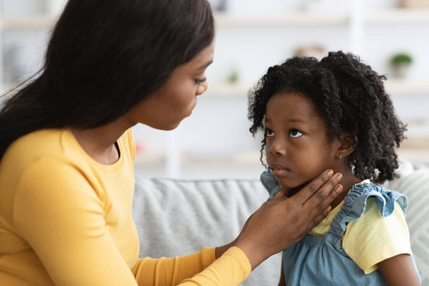 Schwarze Mutter kümmert sich um ihr krankes Kind mit Halsschmerzen - Foto, Bild