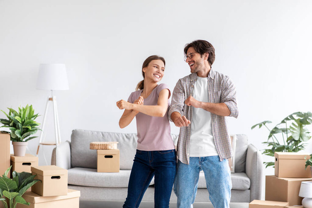 Smiling young caucasian male and female in casual dance and have fun together enjoy relocation in room - Photo, Image