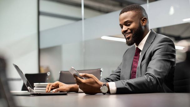 Bonito homem de negócios negro usando gadgets modernos no processo de negócios, panorama - Foto, Imagem