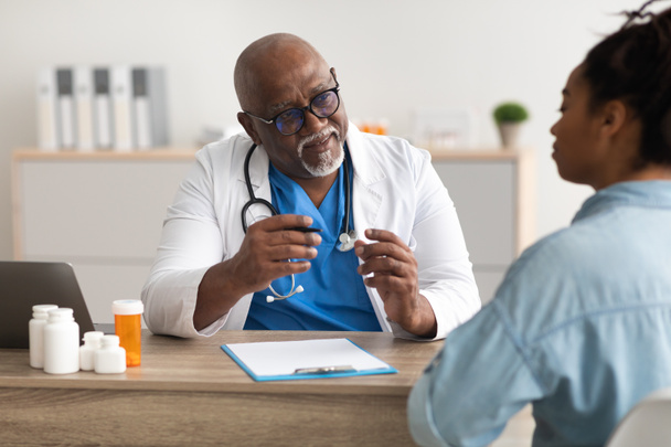 Experienced black doctor explaining treatment plan to patient - Foto, afbeelding