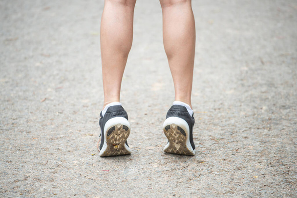 Koşucu kadının koşmadan önce esneyip bacaklarını ısıttığı görüntüler. Esneme hareketi esnekliği artırabilir ve yaralanma riskini azaltabilir..  - Fotoğraf, Görsel