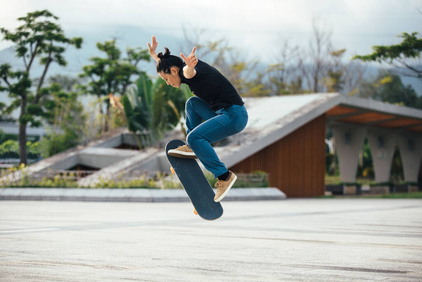 Asian woman skateboarder skateboarding in modern city - Foto, afbeelding
