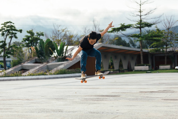 Asian woman skateboarder skateboarding in modern city - Foto, afbeelding