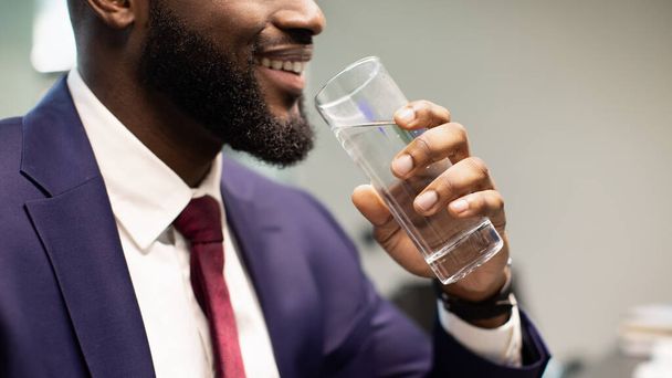 Unrecognizable bearded black man in suit drinking water - Foto, imagen