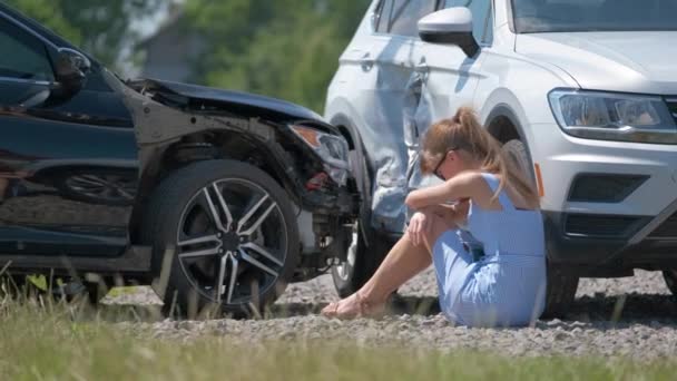 Een gestresste vrouw die op straat zat, geschokt na een auto-ongeluk. Verkeersveiligheid en verzekeringsconcept - Video