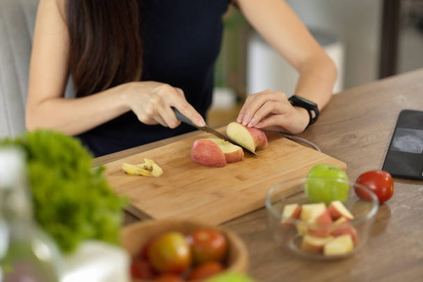Großaufnahme, Frau schneidet rote Äpfel auf Schneidebrett und bereitet ihren gesunden Diät-Snack zu. Kochen zu Hause. - Foto, Bild
