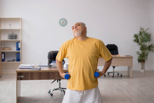 Starý podnikatel zaměstnanec dělá sportovní cvičení v kanceláři - Fotografie, Obrázek