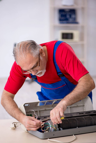 Old repairman repairing air-conditioner at workshop - Photo, Image