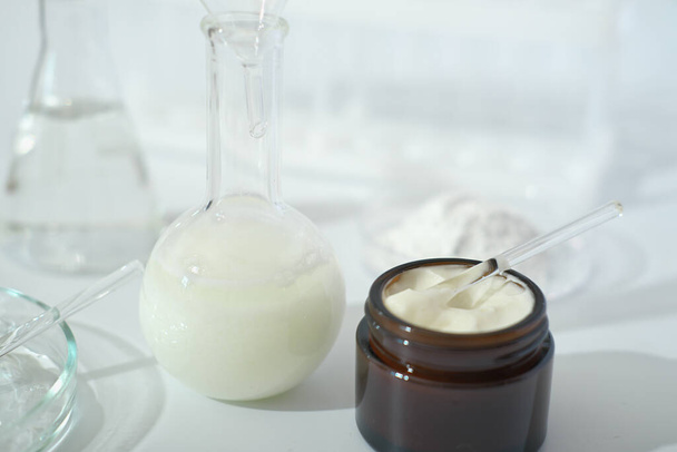 laboratory dishes and glassware on a lab table. fermentation, fermented beauty skin care. container with cream or solution or serum for anti age treatment - Photo, Image