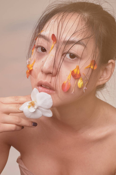 aziatische vrouw met bloemen op haar gezicht - Foto, afbeelding