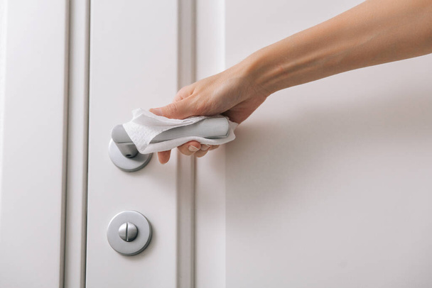 Cleaning door handles with an antiseptic wet wipe and gloves. Woman hand using towel for cleaning home room door link. Sanitize surfaces prevention in hospital and public spaces against corona virus - Foto, Imagem