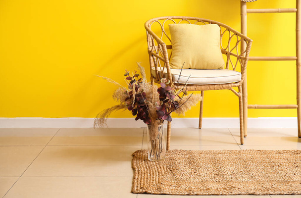 Cadeira de vime, vaso com flores secas e tapete elegante no interior do quarto - Foto, Imagem