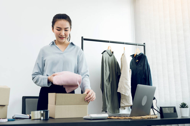 Imprenditore asiatico sta preparando i suoi vestiti che possono essere venduti in scatole di carta per la consegna ai clienti. - Foto, immagini
