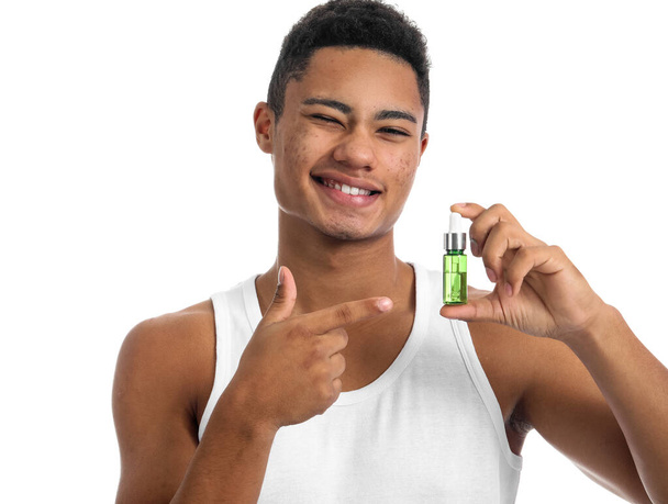 Young African-American guy with serum for skin care on white background - Фото, зображення