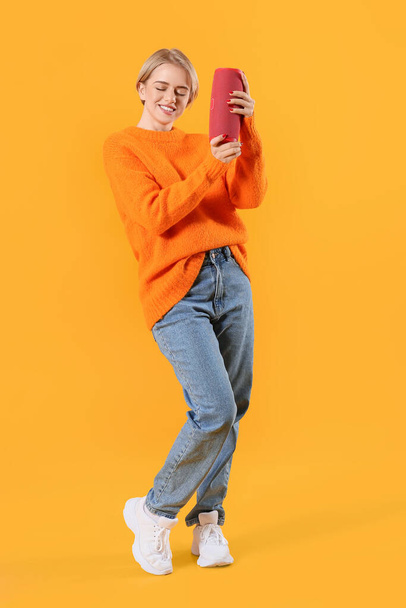 Smiling woman with modern wireless portable speaker on color background - Zdjęcie, obraz