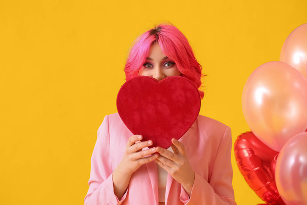 Статильна жінка з яскравим волоссям, подарунком і повітряними кулями на кольоровому фоні. День святого Валентина. - Фото, зображення
