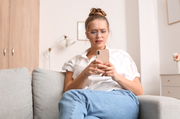Stressed young woman using mobile phone at home - Valokuva, kuva