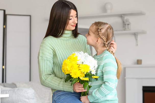 Jonge moeder en haar dochtertje in truien met bloemen thuis - Foto, afbeelding
