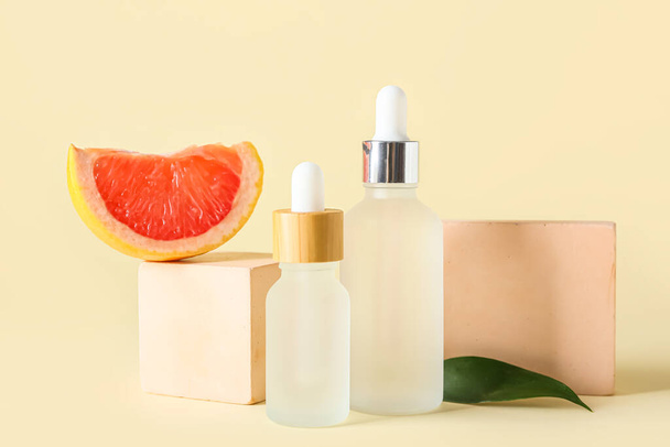 Composición con botellas de aceite esencial, rodajas de pomelo y decoración sobre fondo de color - Foto, Imagen