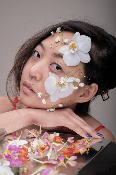 Asian woman with flowers on her face - 写真・画像