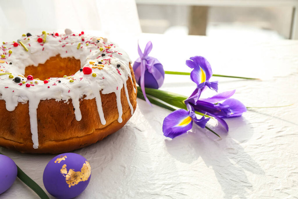 Tasty Easter cake with eggs and flowers on light background - Foto, afbeelding