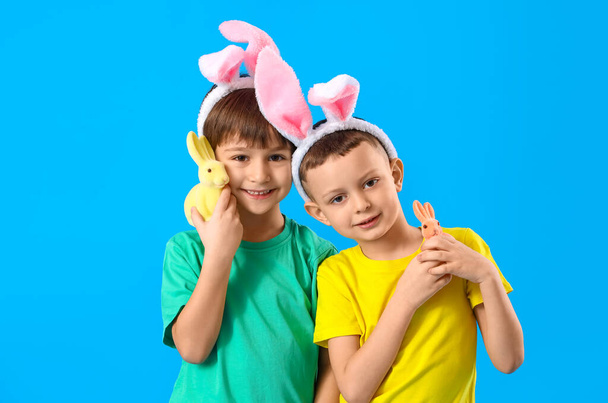 Petits garçons mignons avec des oreilles de lapin et des lapins jouets sur fond bleu - Photo, image
