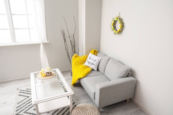 Interior de la moderna sala de estar con sofá, mesa y corona de Pascua - Foto, imagen