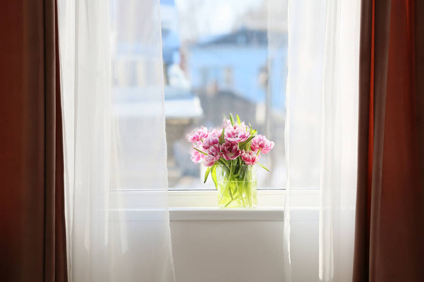 Szklany wazon z pięknymi kwiatami tulipanów na parapecie - Zdjęcie, obraz