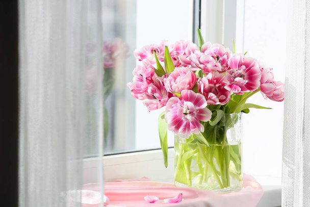 Стеклянная ваза из красивых тюльпанов на подоконнике - Фото, изображение