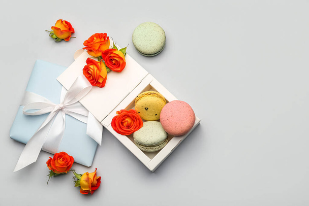 Composición con macarrones dulces y flores de rosas sobre fondo blanco. Celebración del Día Internacional de la Mujer - Foto, imagen