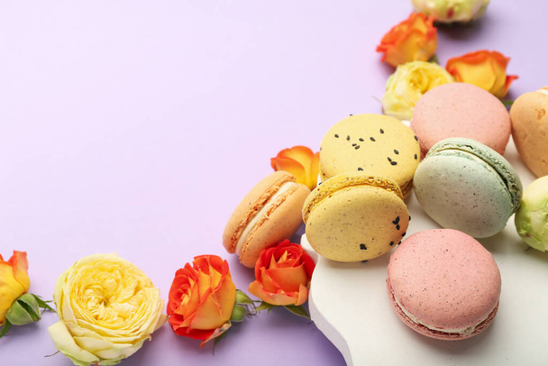 Samenstelling met zoete macarons en rozenbloemen op lila achtergrond, close-up. Internationale Vrouwendag viering - Foto, afbeelding