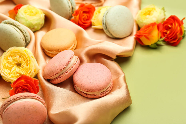 Composition with sweet macaroons and rose flowers on green background, closeup. International Women's Day celebration - Fotó, kép