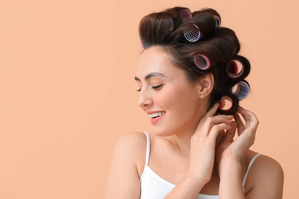 Beautiful young woman in hair rollers on color background - Foto, Imagem