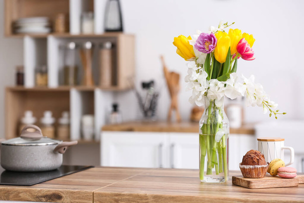 Tasty breakfast and vase with beautiful flowers on wooden kitchen counter - 写真・画像