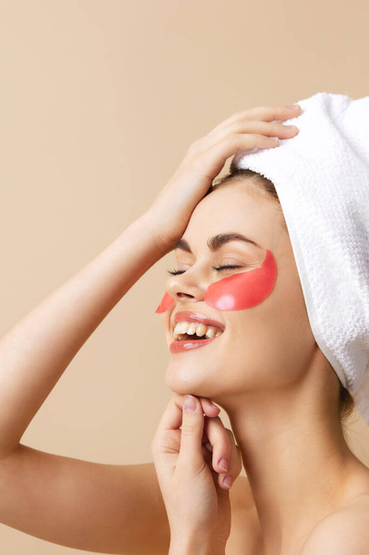 krásná žena s růžovými skvrnami na tváři s ručníkem na hlavě na béžovém pozadí. Kvalitní fotografie - Fotografie, Obrázek