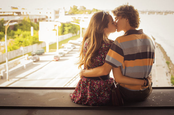 Jeune couple embrasser dans la lumière du jour d'été sur une construction de pont
 - Photo, image