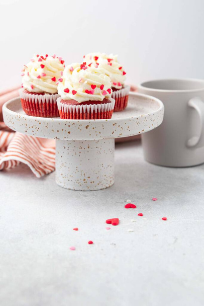Red velvet cupcake with cream cheese frosting and red hearts sprinkles on the top. Valentine's Day concept. Selective focus. - 写真・画像