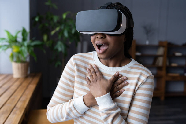 Aufgeregte Afroamerikanerin mit weit geöffnetem Mund erlebt virtuelles Gaming zum ersten Mal - Foto, Bild