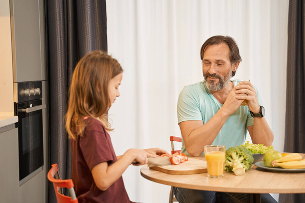 Uomo adulto seduto con sua figlia al tavolo della cucina - Foto, immagini